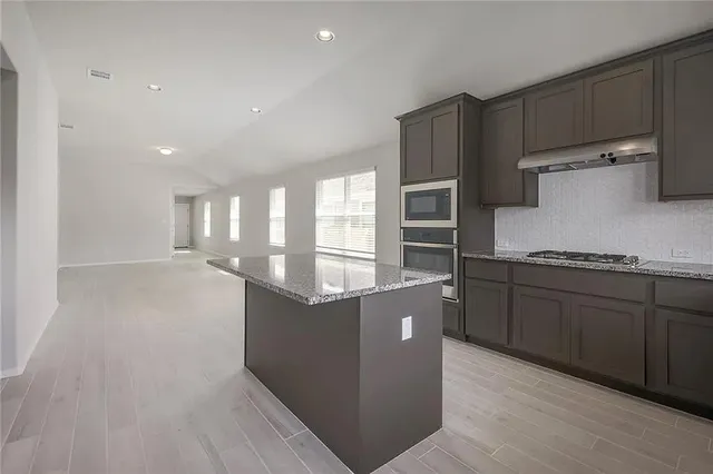 a kitchen with kitchen island wooden cabinets and stainless steel appliances