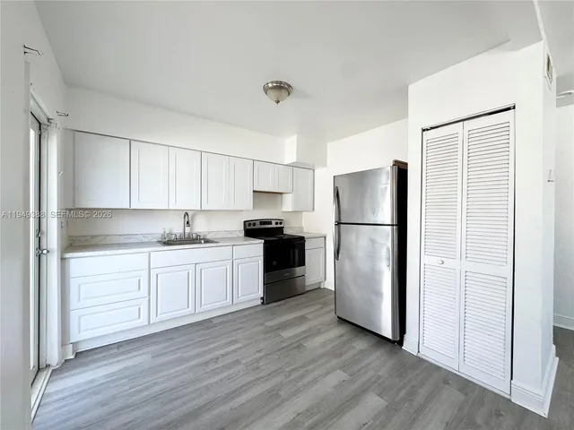 a kitchen with a refrigerator and white cabinets