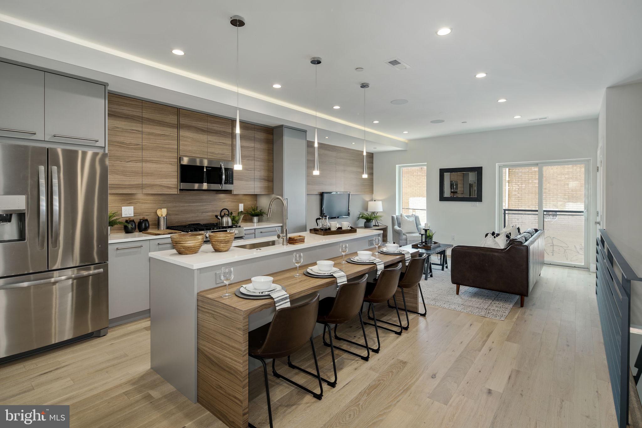 a large kitchen with kitchen island a large counter top dining table and stainless steel appliances