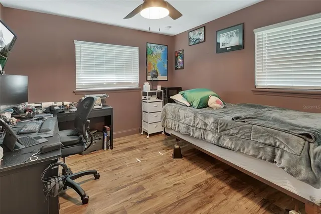 a bedroom with a bed a desk and chair with window