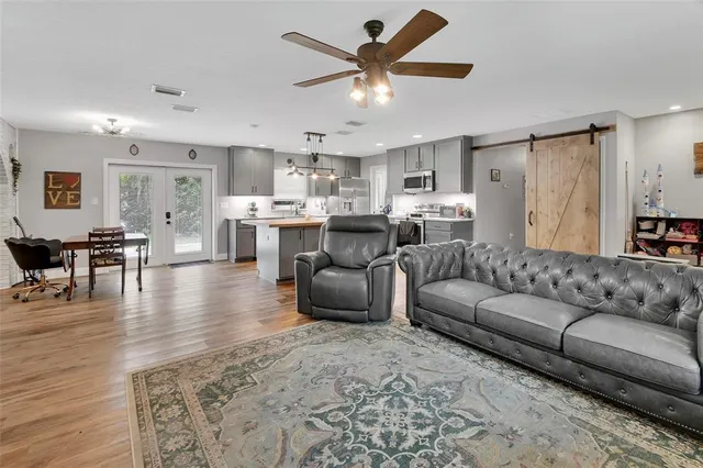 a living room with furniture kitchen view and a wooden floor