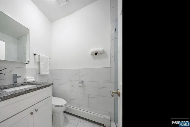 a bathroom with a granite countertop toilet and sink