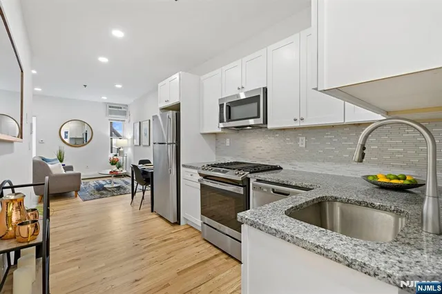 a kitchen with a sink dishwasher a stove and a microwave oven with wooden floor