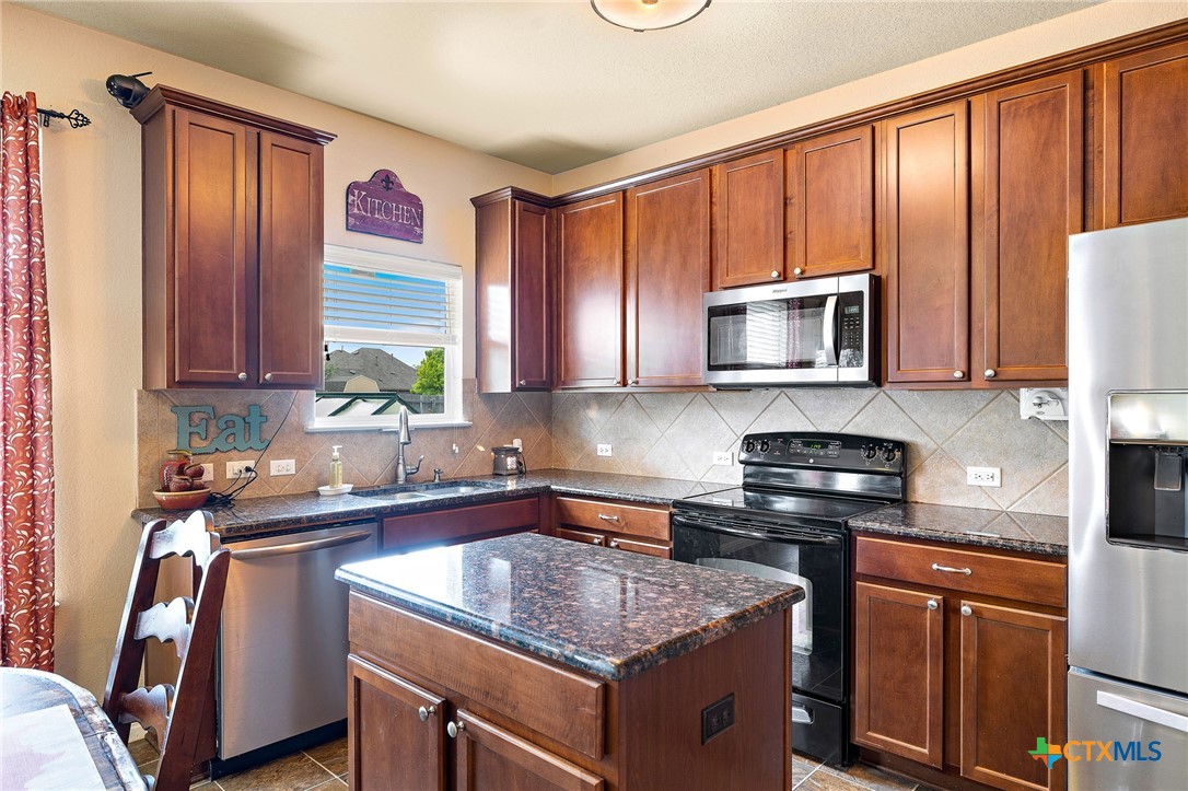 326 Comal Run Hutto, TX 78634 - Photo 5 of 23 a kitchen with stainless steel appliances granite countertop a sink stove and microwave
