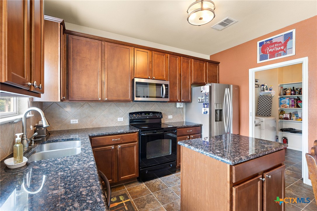326 Comal Run Hutto, TX 78634 - Photo 7 of 23 a kitchen with granite countertop a stove top oven a sink dishwasher a dining table and chairs with wooden floor