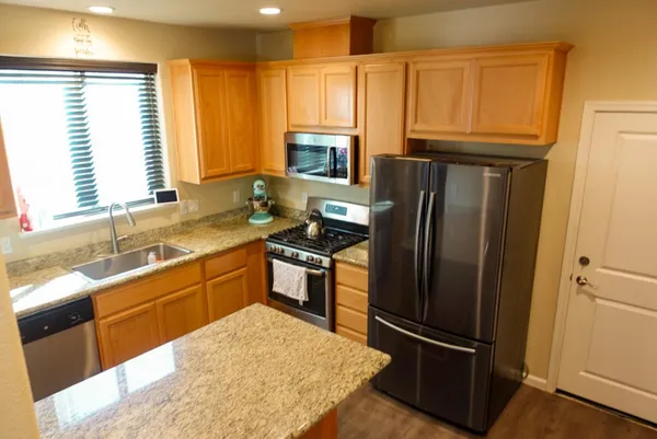 a kitchen with granite countertop stainless steel appliances a refrigerator stove and sink