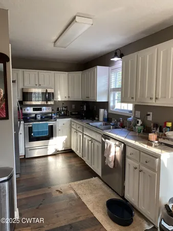 a kitchen with stainless steel appliances kitchen island granite countertop a stove sink and cabinets