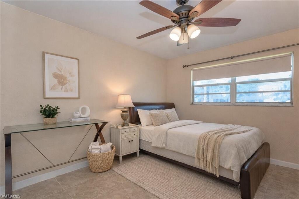 4290 Gulfstream Drive, Unit 5 Naples, FL 34112 - Photo 9 of 16 a bedroom with bed and a chandelier