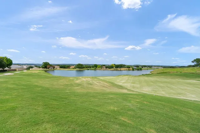 a view of a lake with beach and house in the back