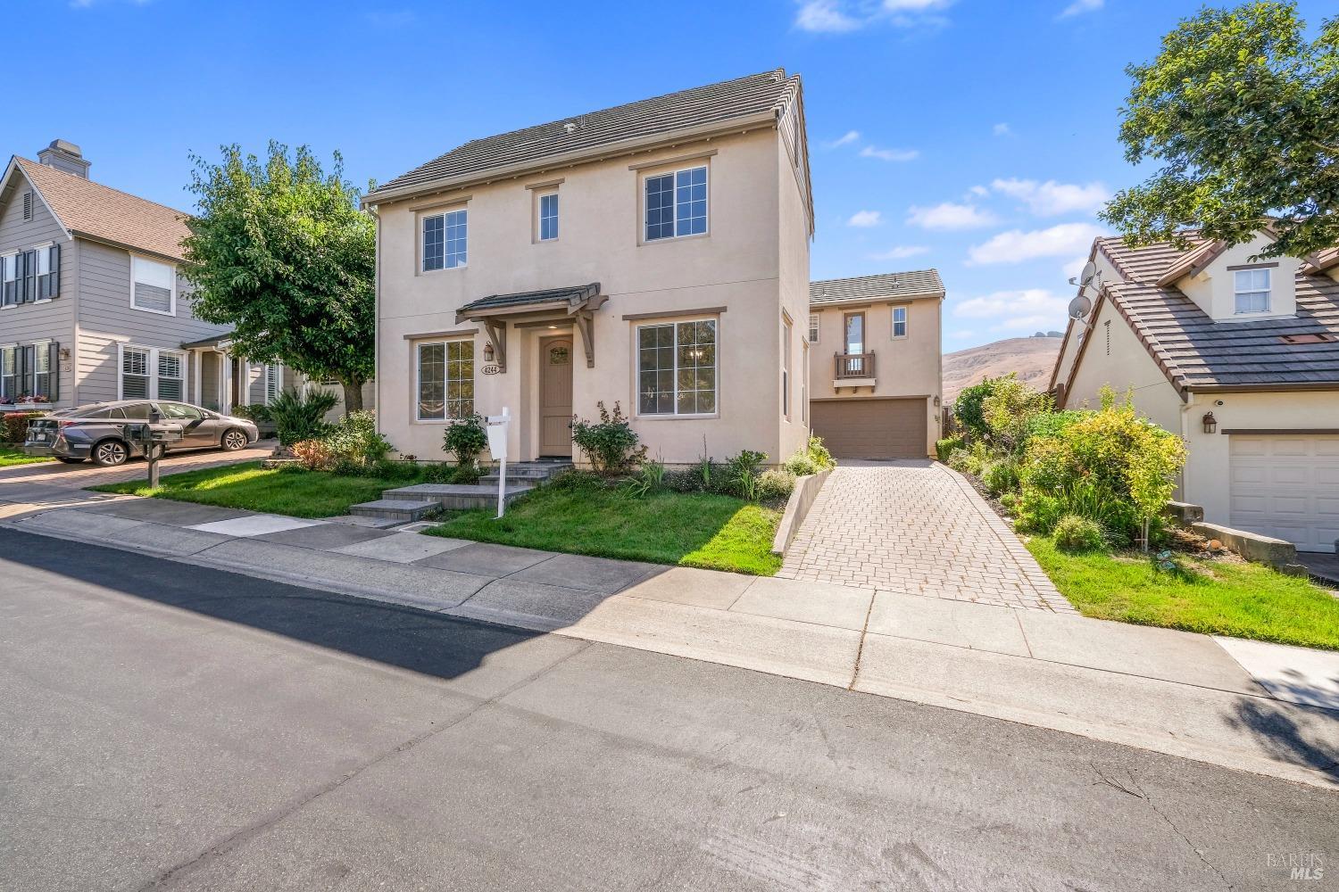 a view of a white house with a yard plants and palm trees