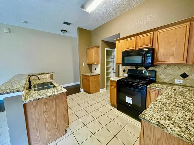 a kitchen with stainless steel appliances granite countertop a stove a sink and a microwave