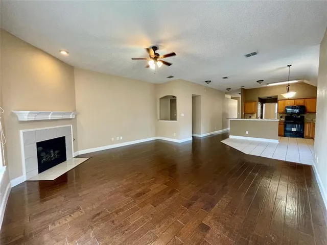 a view of a livingroom with fireplace wooden floor and a ceiling fan