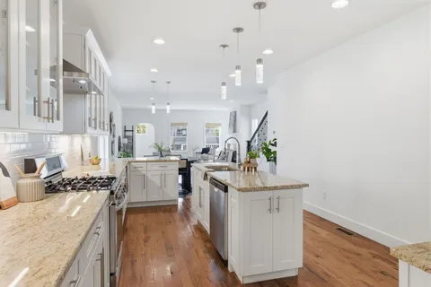 a kitchen with stainless steel appliances granite countertop a lot of counter space and wooden floors
