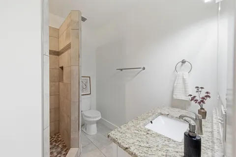 a bathroom with a granite countertop sink a toilet and shower