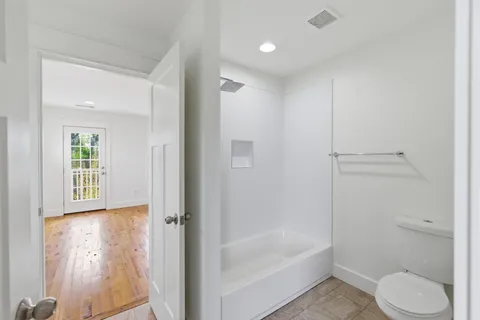 a bathroom with a granite countertop bathtub shower sink vanity and toilet