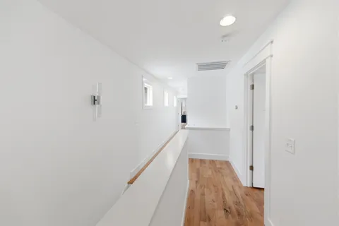 a view of a hallway with wooden floor and staircase