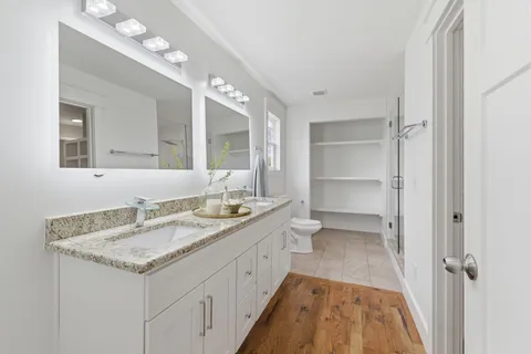 a bathroom with a granite countertop sink a mirror and a toilet