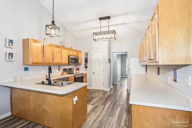 a kitchen with stainless steel appliances a sink dishwasher a refrigerator and a stove with wooden floor