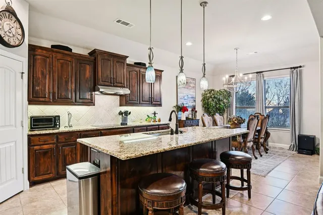 a kitchen with granite countertop a table chairs stove top oven and refrigerator
