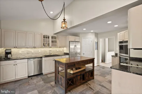 a kitchen with stainless steel appliances granite countertop a stove a sink and a refrigerator