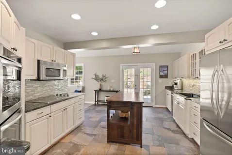 a large kitchen with stainless steel appliances granite countertop a lot of counter space and a sink