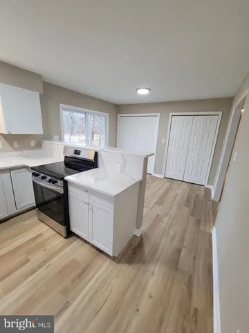 a kitchen with wooden floors and white stainless steel appliances