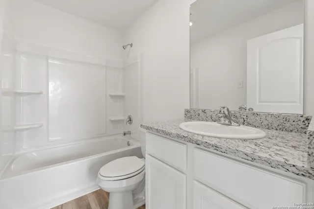 a bathroom with a granite countertop toilet sink and mirror