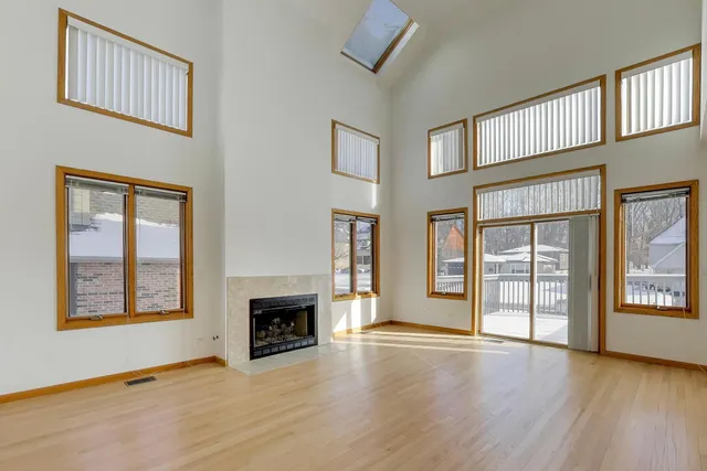an empty room with wooden floor fireplace and windows
