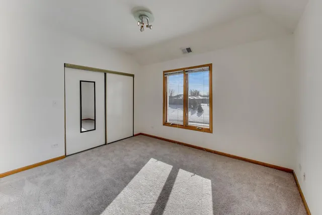 a view of an empty room with window and closet area