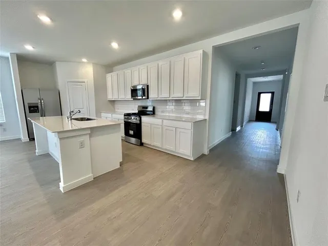 a large kitchen with stainless steel appliances kitchen island granite countertop a large counter top and wooden floors