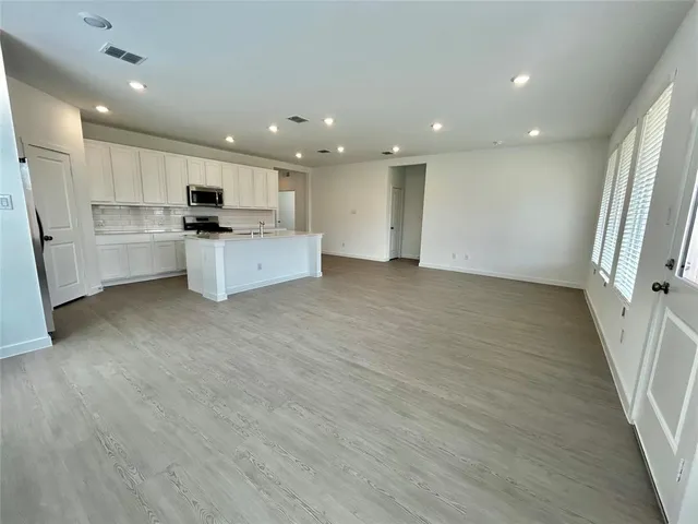 a kitchen with stainless steel appliances granite countertop a stove top oven a sink a refrigerator and white cabinets