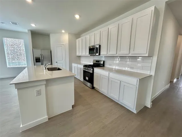 a kitchen with white cabinets and stainless steel appliances