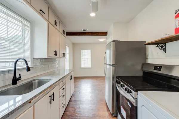 a kitchen with granite countertop a sink stove and refrigerator