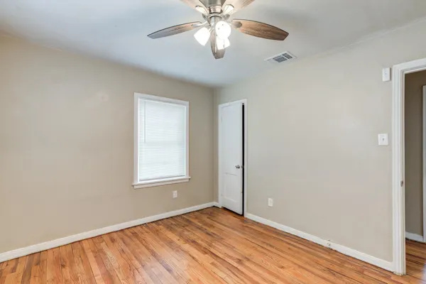 a view of an empty room with window and wooden floor