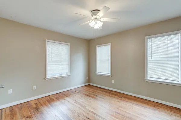 a view of an empty room with a window and wooden floor