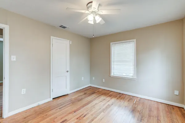 a view of empty room with wooden floor and fan