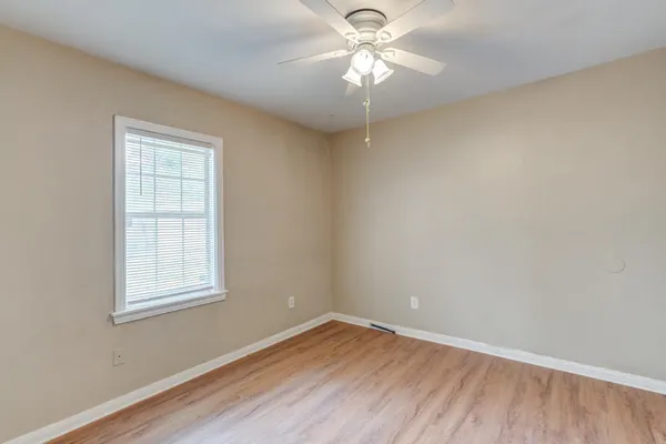 an empty room with a window and a fan