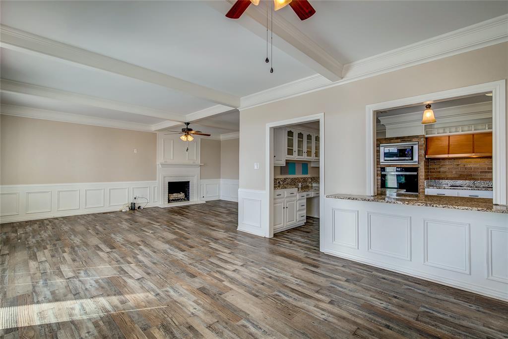 7359 Highway 154 Sulphur Springs, TX 75482 - Photo 17 of 40 breakfast area with great room beyond; pass through to kitchen; note the ceiling beams, wainscoting, crown molding, and fireplace with hearth