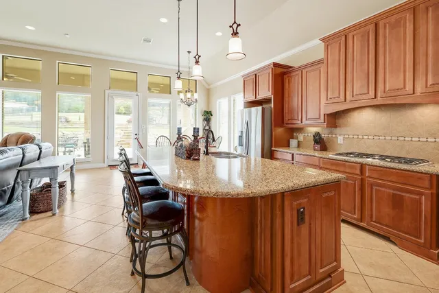 a kitchen with stainless steel appliances granite countertop a sink a stove and a wooden cabinets