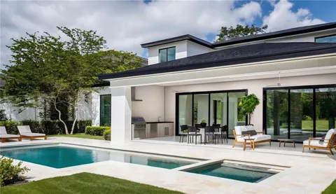 a view of a swimming pool with chairs and tables in patio