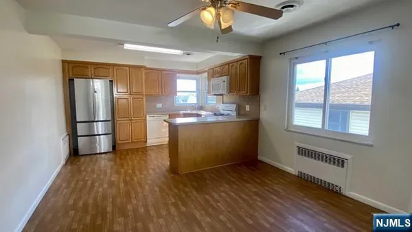 a kitchen with stainless steel appliances granite countertop a refrigerator a sink dishwasher a stove and white countertops with wooden floor