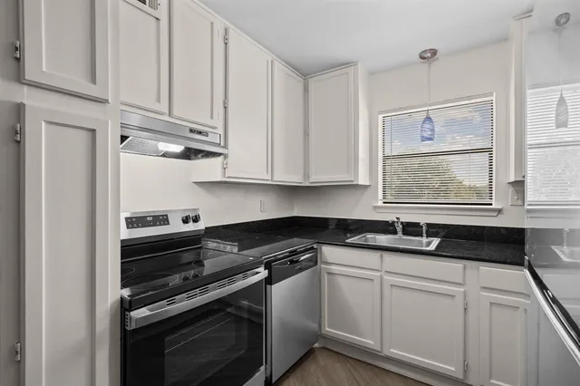 a kitchen with granite countertop white cabinets and stainless steel appliances