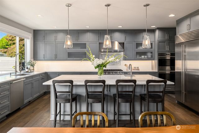 a kitchen with stainless steel appliances kitchen island granite countertop a dining table chairs refrigerator and sink