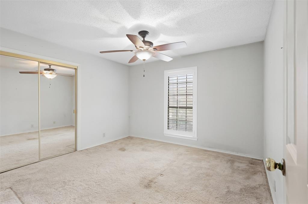 37 Timbergreen Circle Denton, TX 76205 - Photo 21 of 31 White-painted walls with textured ceiling, ceiling fan with integrated lighting, window with blinds, and mirrored closet doors with gold-tone frames