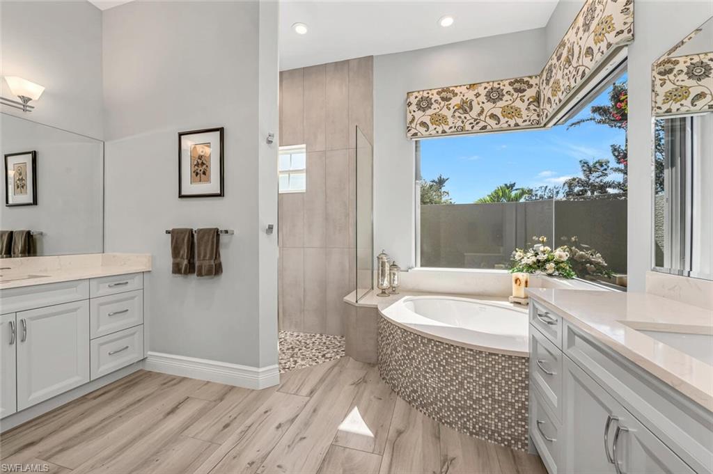 2067 Mission Drive Naples, FL 34109 - Photo 27 of 43 a spacious bathroom with a double vanity sink a mirror a bathtub and shower