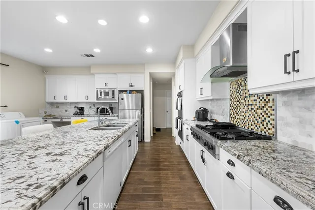 a large kitchen with stainless steel appliances granite countertop a lot of counter space and wooden floors