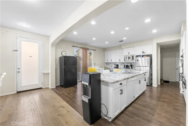 a large white kitchen with sink and stainless steel appliances