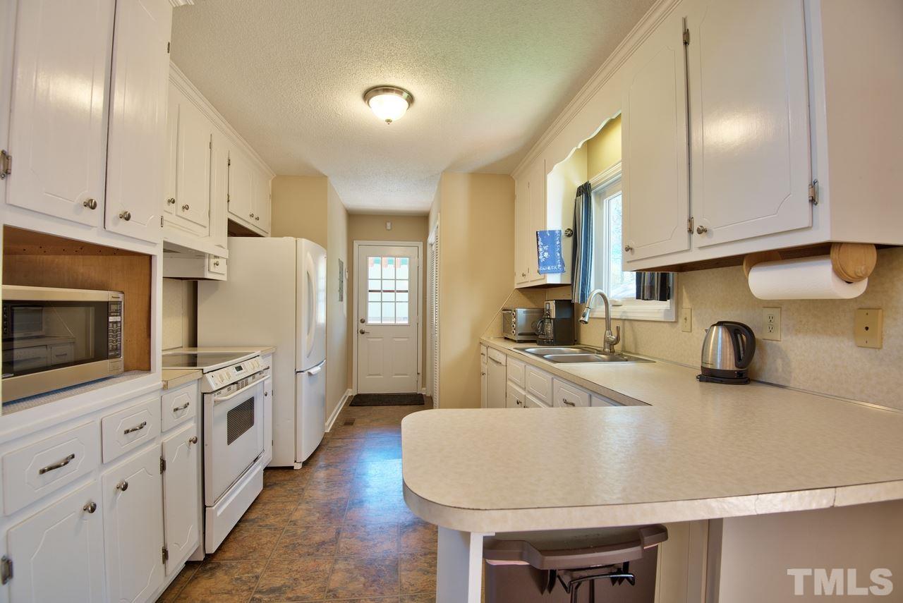 6017 Crabapple Road Durham, NC 27712 - Photo 11 of 18 a kitchen with stainless steel appliances a sink a stove and a refrigerator