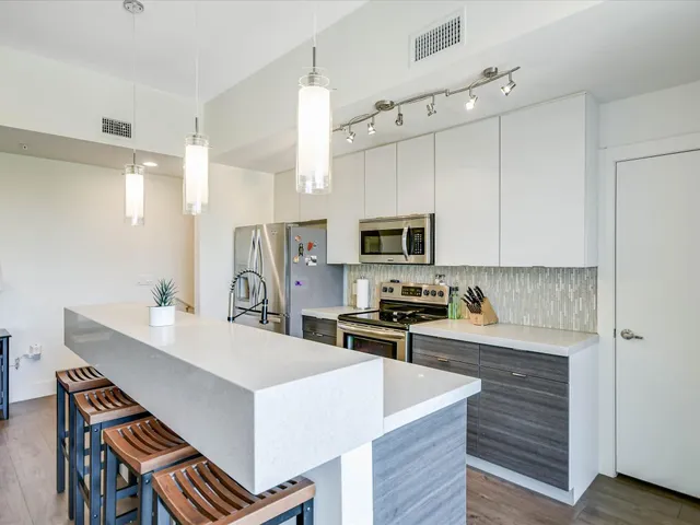 a kitchen with stainless steel appliances a white stove top oven a sink a refrigerator and cabinets