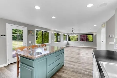 a living room with kitchen island granite countertop wooden floor and a large window